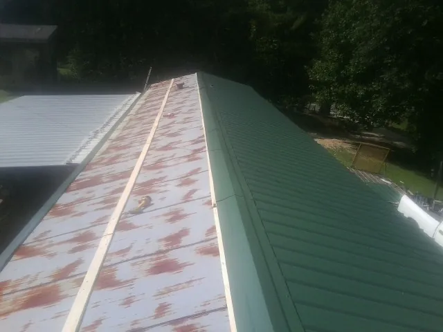 Old rusted panels beside newly installed green metal roofing — Wind Damage Roof Repair by Roofing Brothers in Hensley