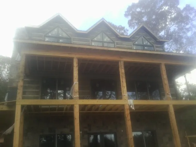 Dormers and porch framing on a large log home under construction — Roof Coating work by our crew in Hensley