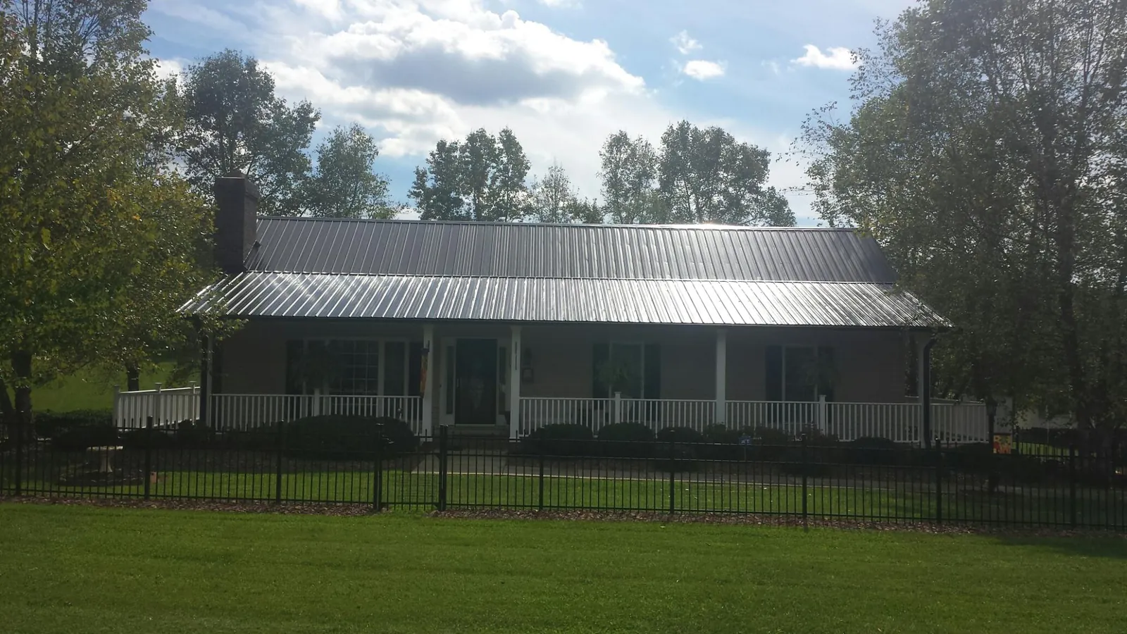 Gray metal roof on a brick ranch with a full width front porch — Gutter Guard Installation work by our crew in Hensley