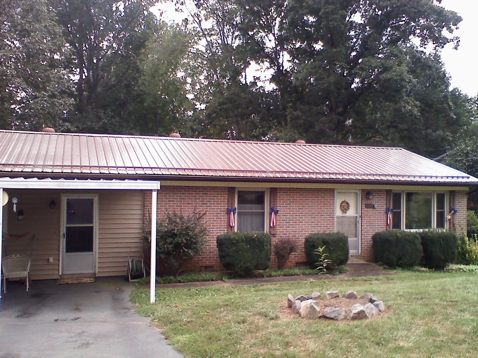 Bronze metal roof and carport on a brick ranch home — Roof Repair work by our crew in Hensley