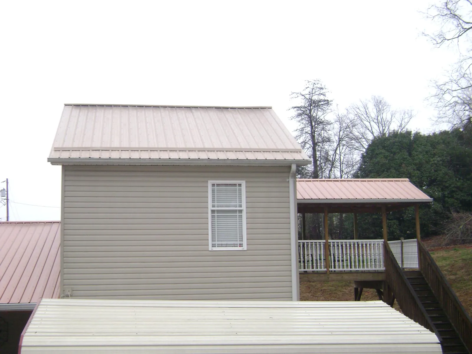 Tan metal roofs on a two story addition and attached porch, from a Roof Replacement job in Hensley