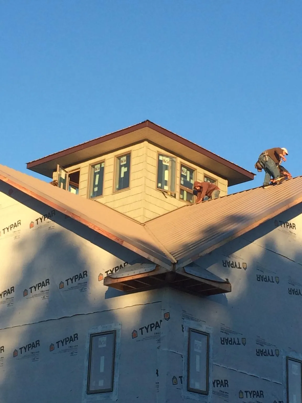 Roofers working around a rooftop cupola on a new metal roof at sunset — Roof Waterproofing in Hensley by Roofing Brothers